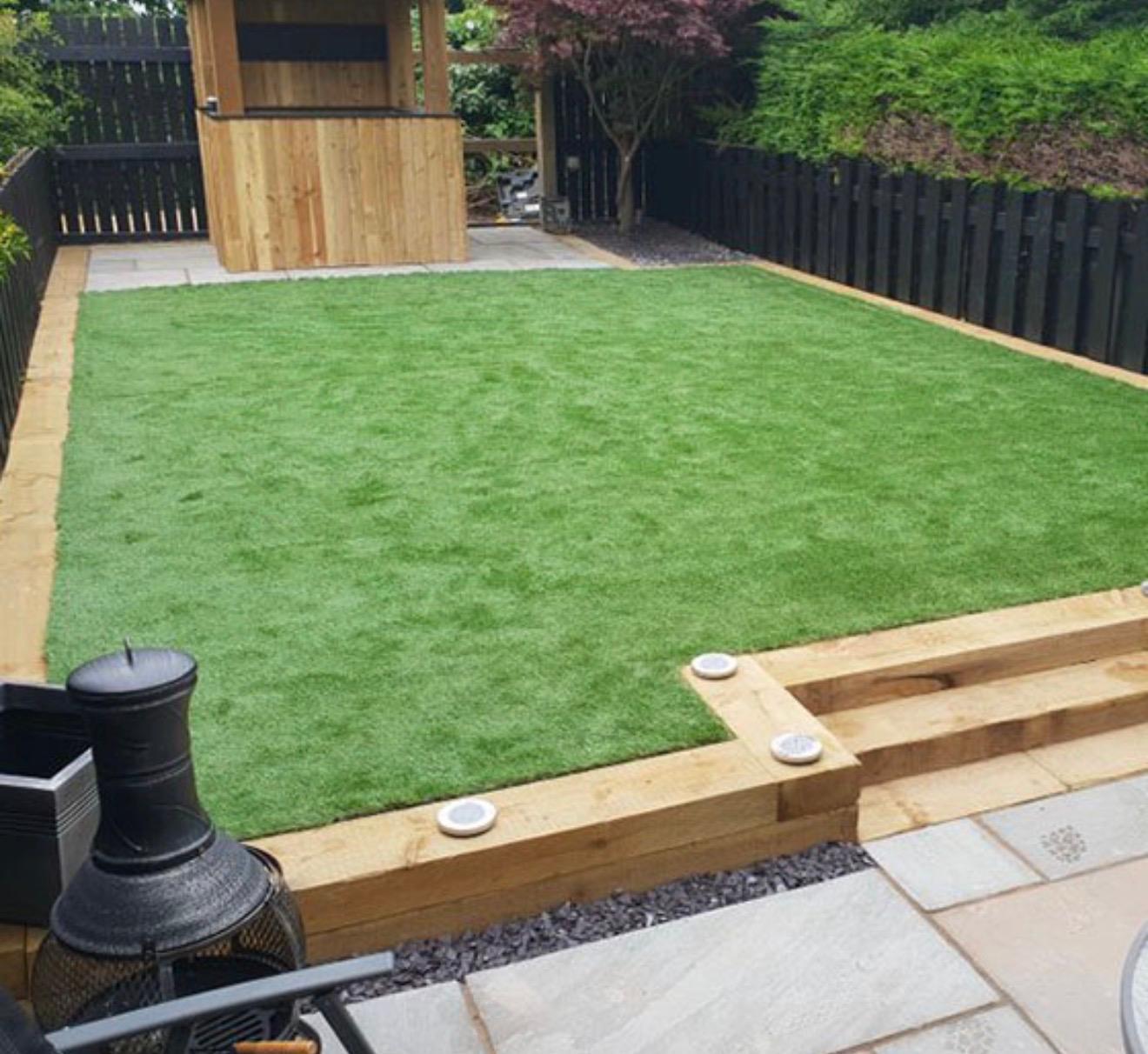 Artificial grass lawn with timber sleeper edging and sandstone patio