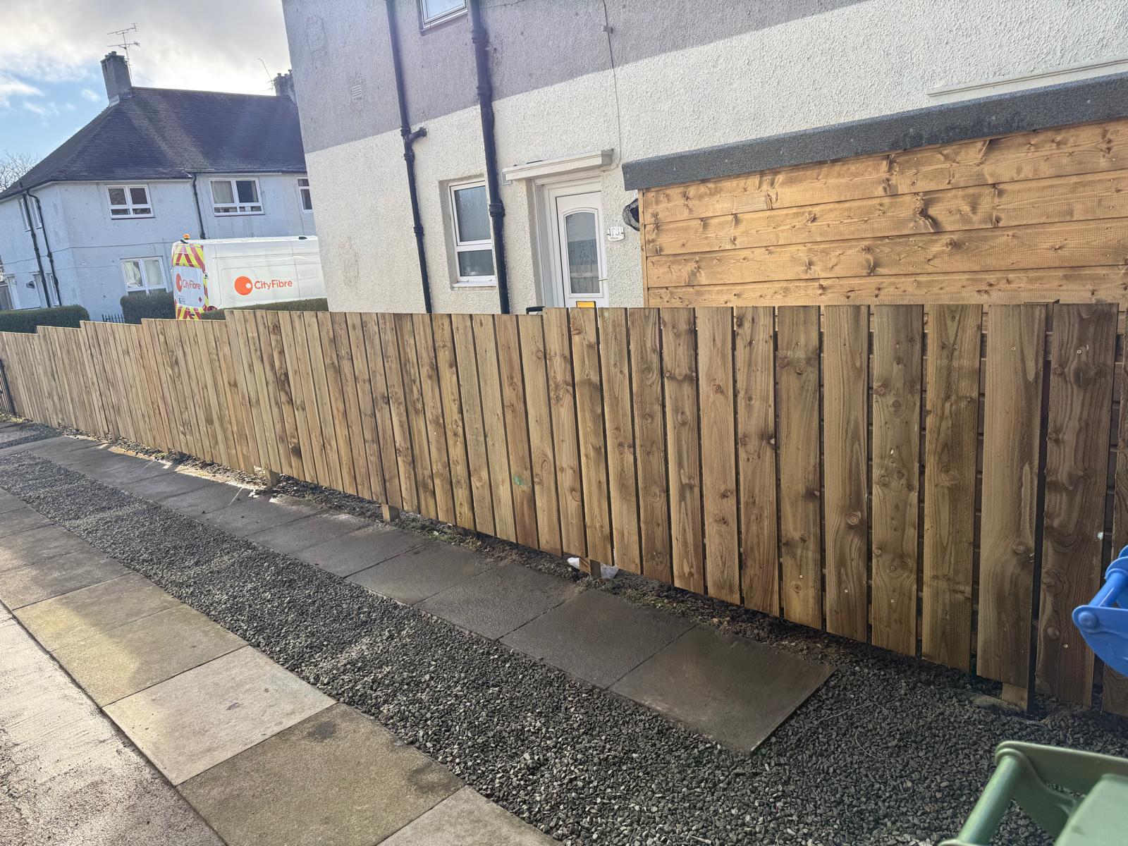 Close-board fence with gravel path along side of house