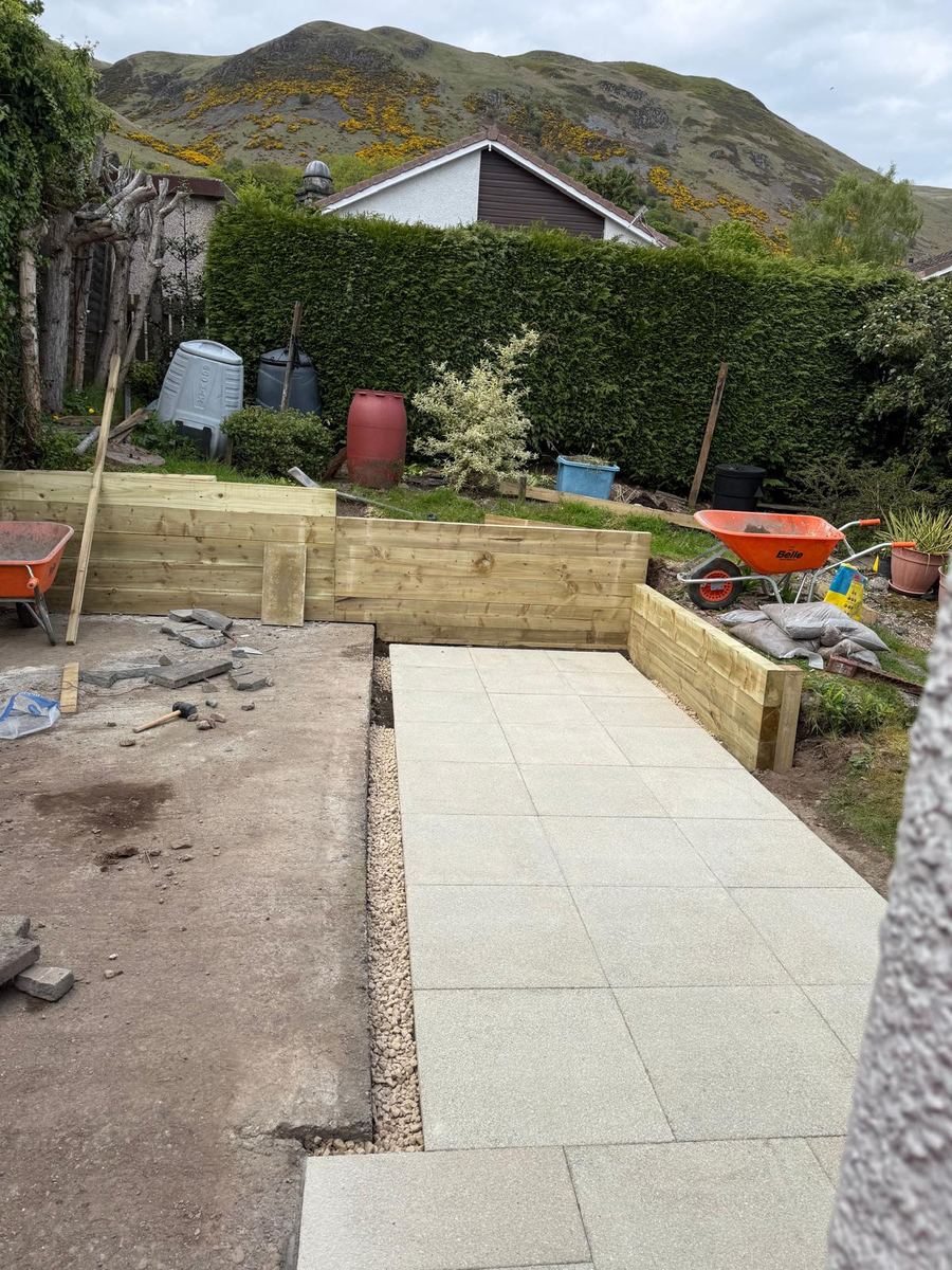 Porcelain patio path with timber sleeper retaining walls and hills behind