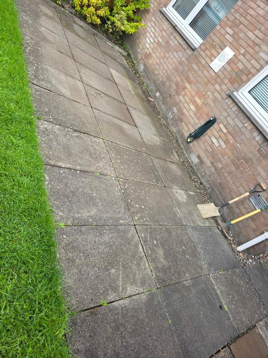 Old cracked concrete slabs down the side of a house before a new sandstone patio