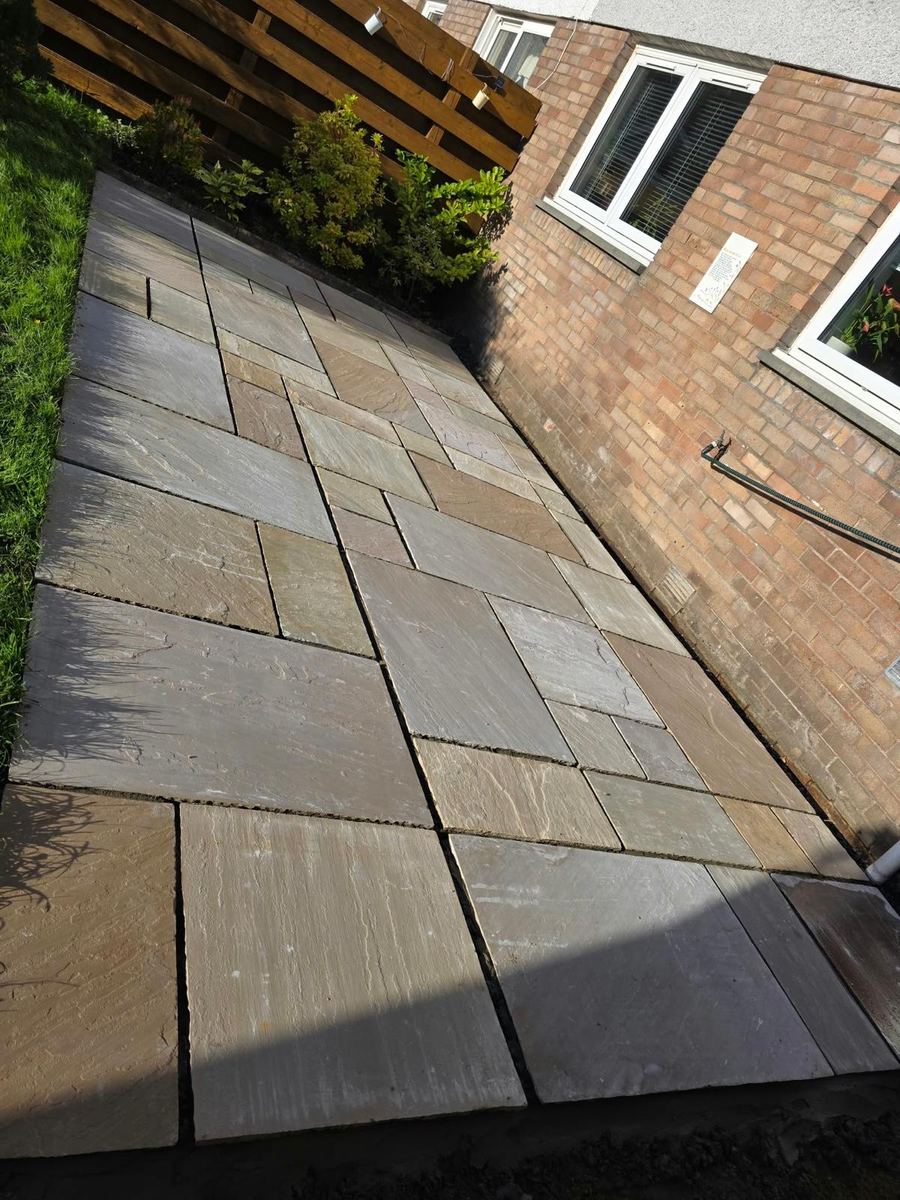 Close view of the finished sandstone patio slabs and gravel drainage strip