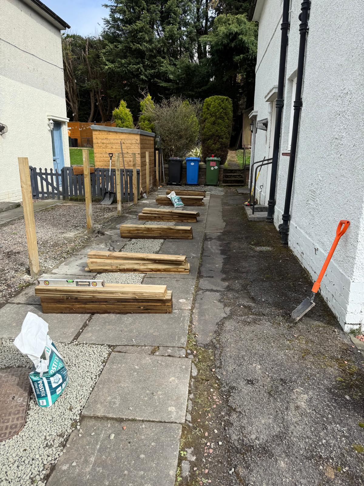 Timber fence materials ready for installation on side path