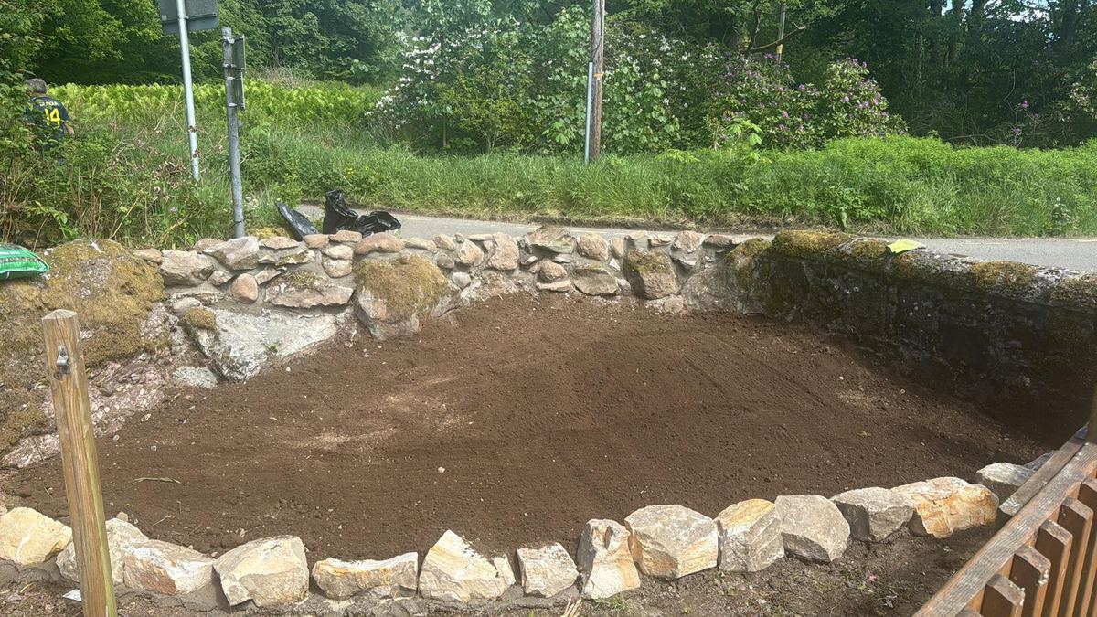 Stone-edged garden bed dug out and prepared for planting