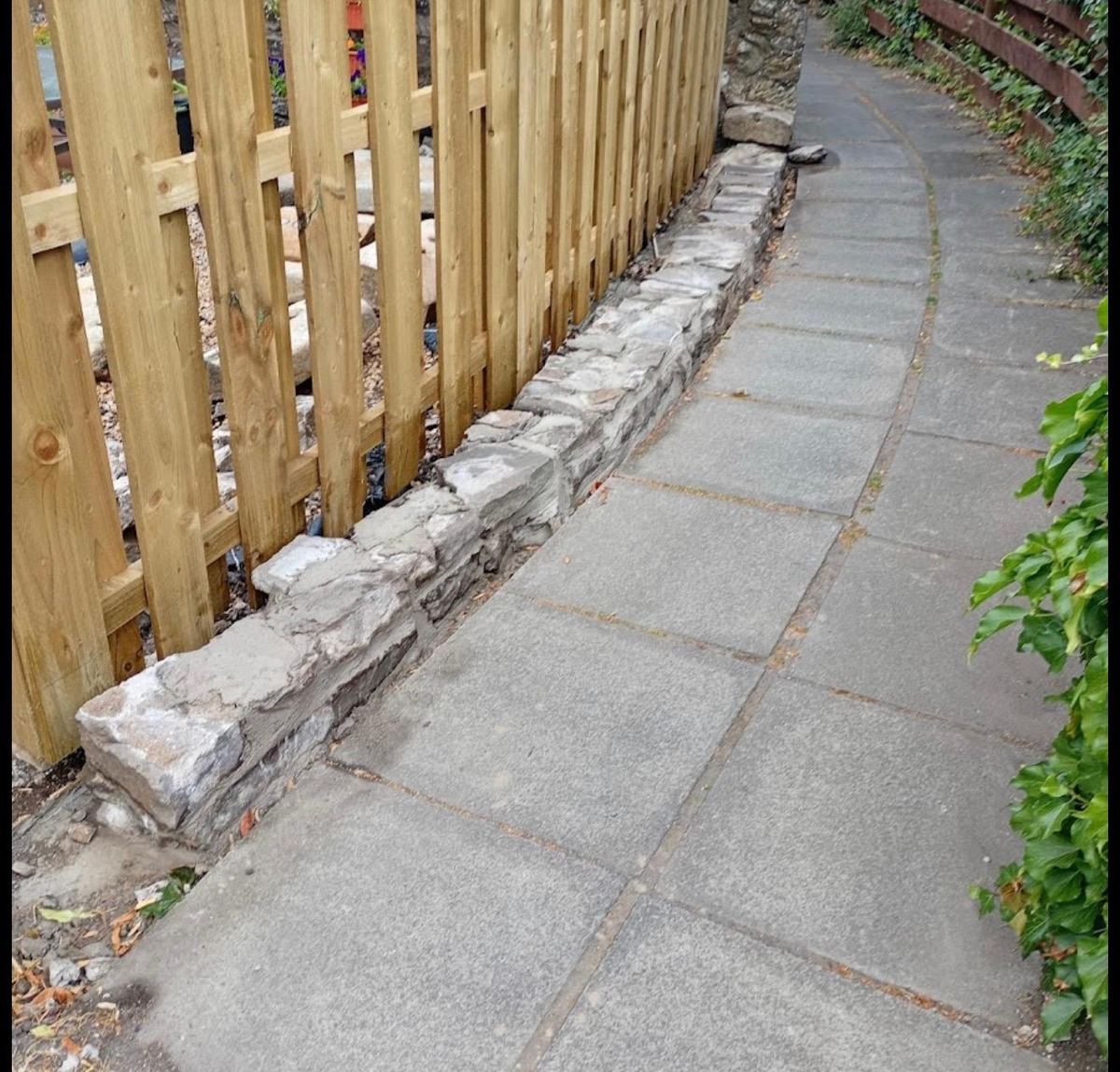 Rebuilt stone dwarf wall with new timber fence along a lane