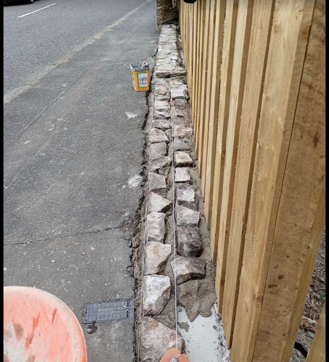 Stone dwarf wall being repaired before a new timber fence