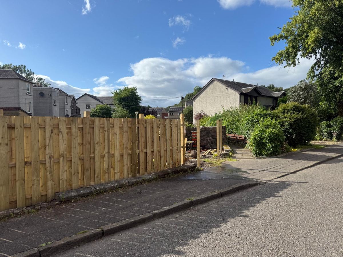 Timber boundary fence on a low wall beside the street